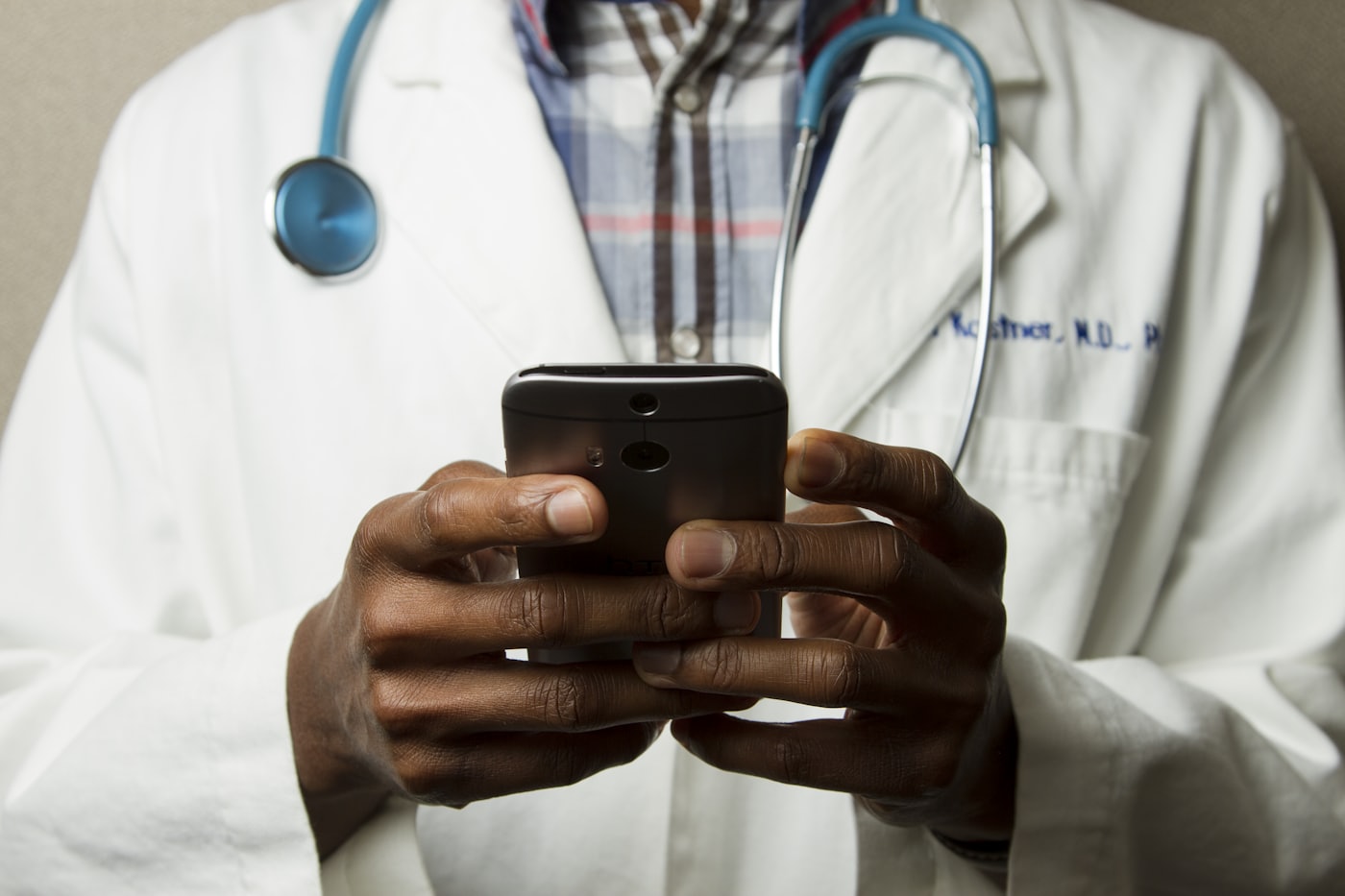 A doctor with a stethoscope checking updates on a mobile device