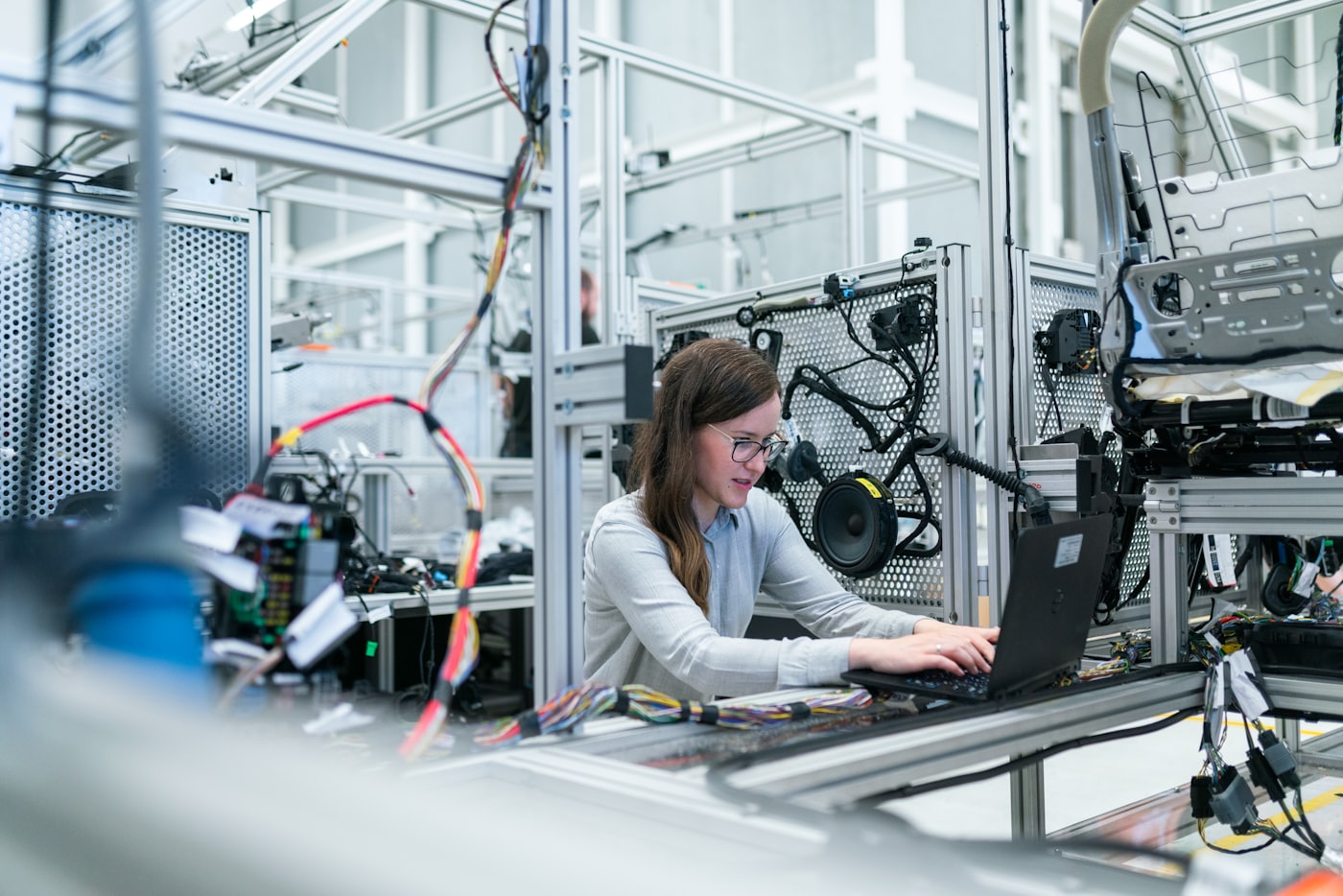 An engineer working on a laptop beside an automated production line