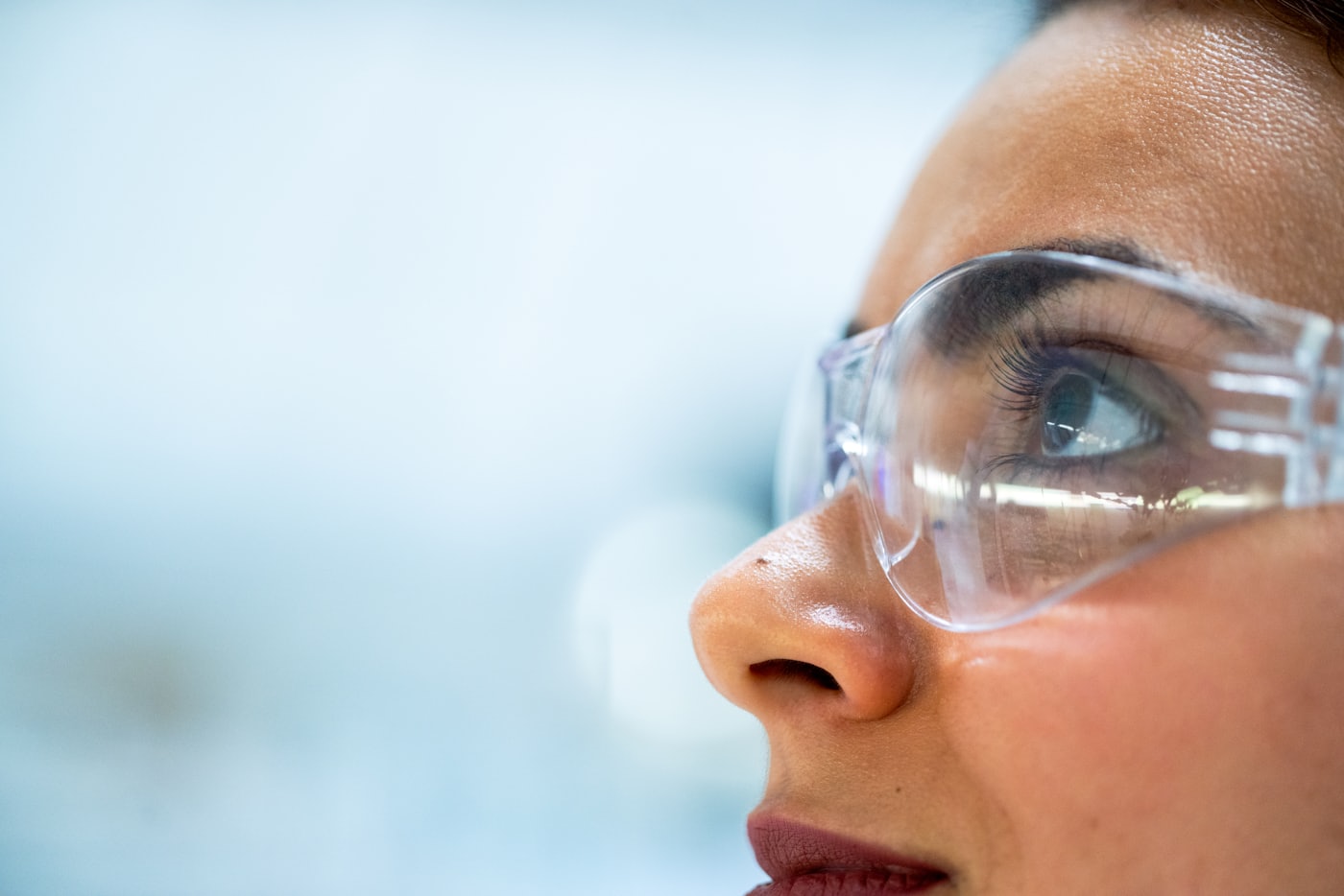 An inspector in safety glasses examining production quality up close