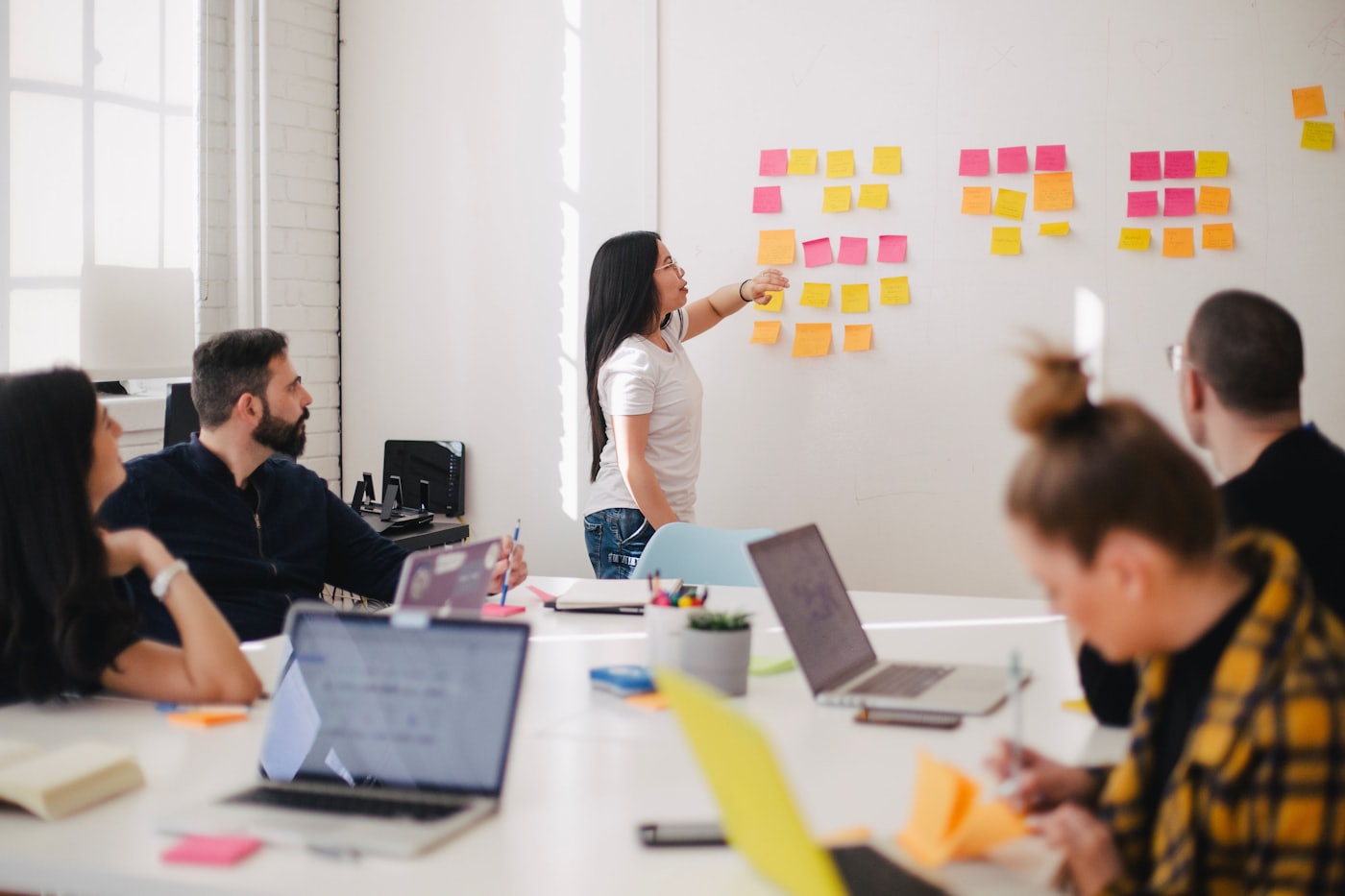 A consultant mapping a process with sticky notes while the team watches